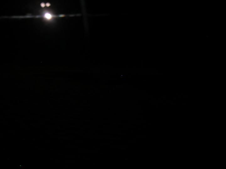 View of the moon over the pacific ocean, taken through the airplane window.  I thought the clouds down below looked amazing, but apparently my camera did not agree.