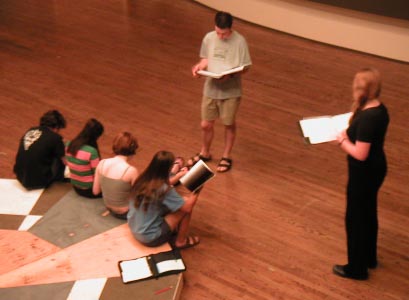 Jesse directs actors sitting on the twelve-side-agon as Grace follows along in her script.